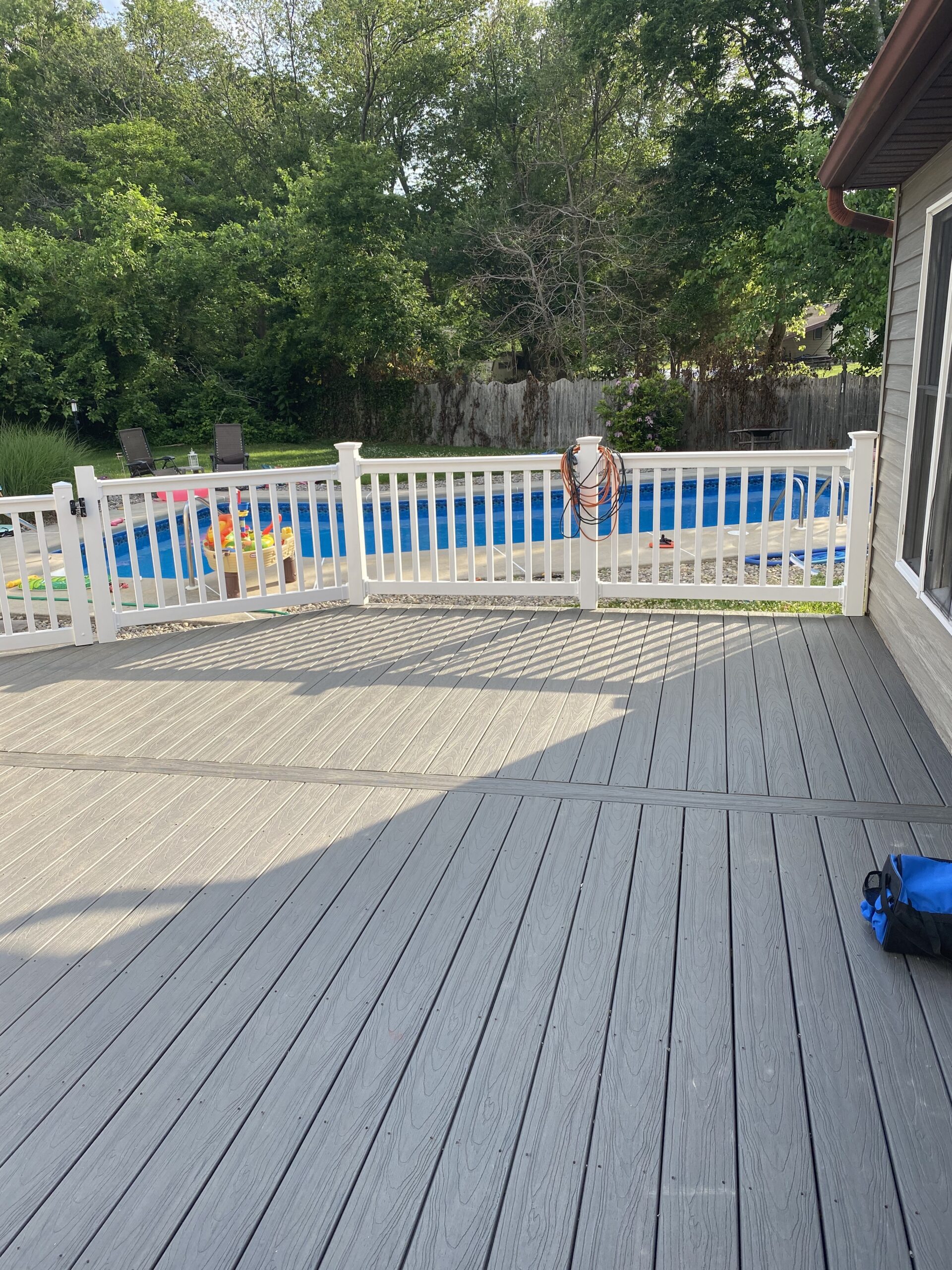A Deck With a White Railing and a Blue Pool