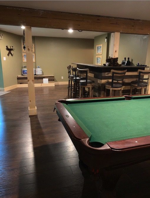 A Basement Pool Table With Bar Stools